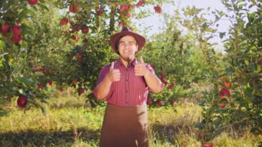 Elma bahçesinde yukarı başparmak gösterilen çiftçi dans