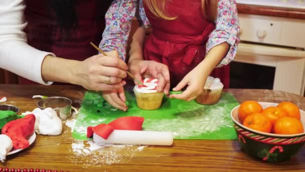 Mère et fille décorent avec du mastic de sucre un cupcake de Noël — Video