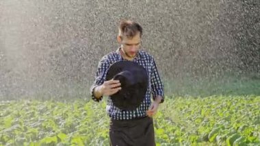 Yorgun çiftçi onun şapkasını plantasyon sulama sırasında alır.