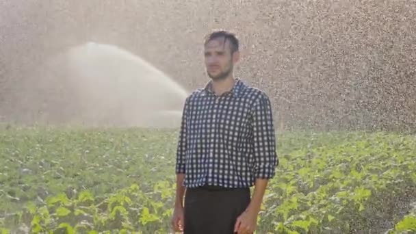 Fermier fatigué debout pendant l'irrigation de la plantation . — Video