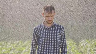 Yağmur altında duran üzgün bir adam portresi. Çok yavaş hareket