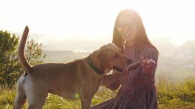 Çok güzel genç kadın ile köpek niteliğine şaşırtıcı günbatımı sırasında oynamaya.
