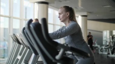 Orta yaş spor salonunda egzersiz bisikleti üzerinde çekici kadın.
