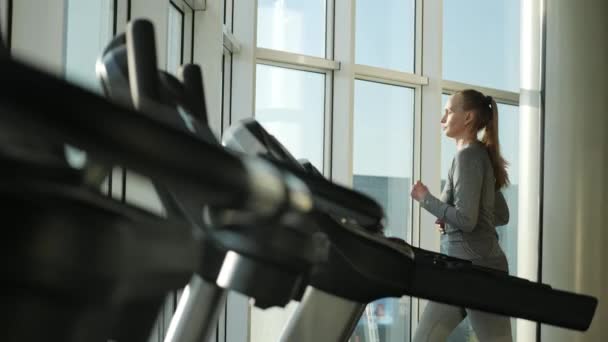 Atractiva mujer de mediana edad se ejecuta en el molino de rodadura en el gimnasio deportivo — Vídeo de stock