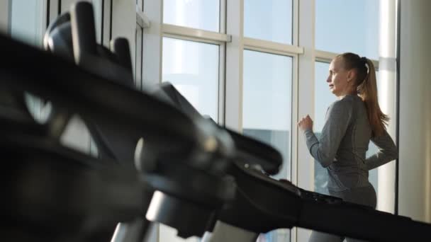 Attractive woman of middle age is running on tread mill in sport gym — Stock Video