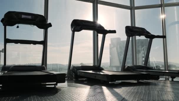 Pohled na běhounu mlýn v tělocvičně sportovní poblíž velké okno. — Stock video