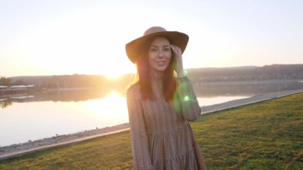 Adorable chica joven sonriendo posando en la cámara durante caminar cerca del lago . — Vídeos de Stock