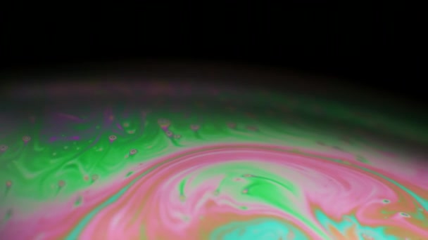 Macro shot des couleurs tourbillonnantes d'une bulle de savon sur fond noir . — Video