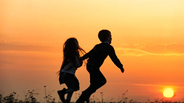 夕暮れ時の 2 人の幸せな子供のシルエット — ストック写真