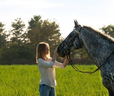 Bir at, bir yeşil yaz çayır üzerinde olan güzel kadın.