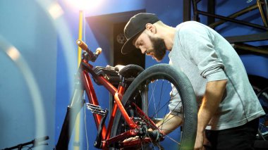 Genç bir mahanic onu onarım atölyesinde bir bisiklet tekerleği sabitleme
