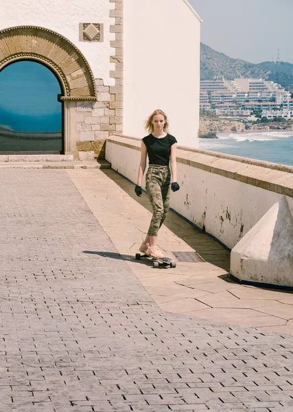 Una bella ragazza bionda sullo skateboard in estate giornata calda sul lungomare — Foto Stock