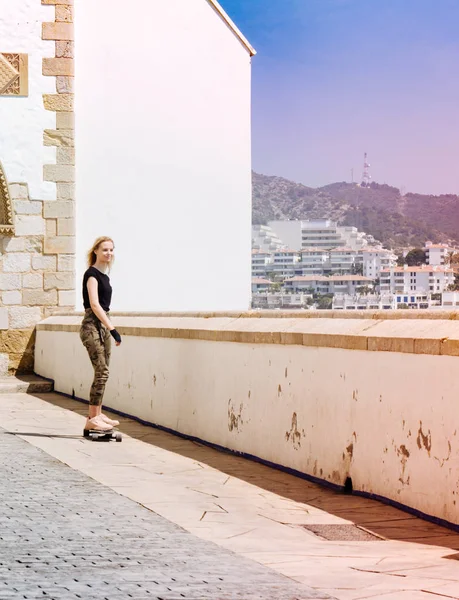 Una bella ragazza bionda sullo skateboard in estate giornata calda sul lungomare — Foto Stock