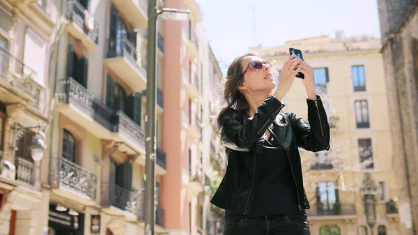 Attraente donna turistica che fa un selfie utilizza uno smartfone mentre cammina per strada. — Foto Stock