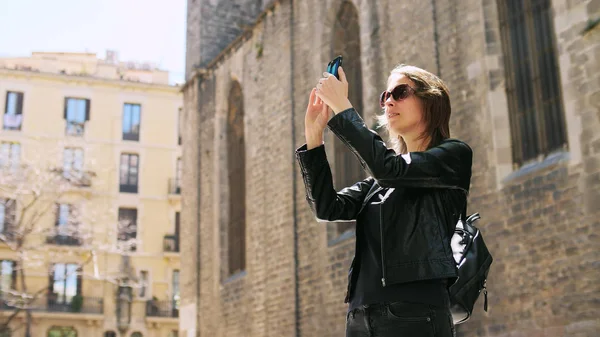 Attraente donna turistica che fa un selfie utilizza uno smartfone mentre cammina per strada. — Foto Stock