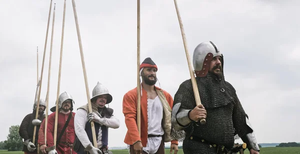 フィールド上で前進する頭の上に槍とヘルメットを持つ中世の騎士のグループ. — ストック写真