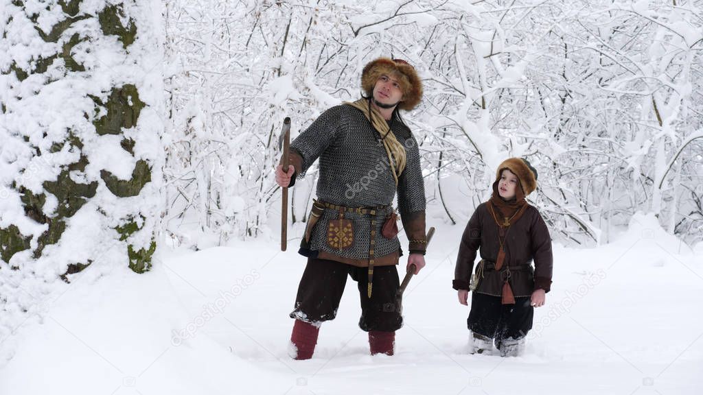 Father viking with his son in the winter forest