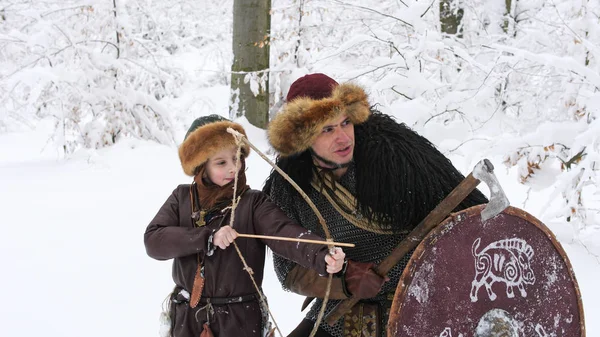 父バイキングは冬の森でアーチェリーに彼の息子を教える. — ストック写真