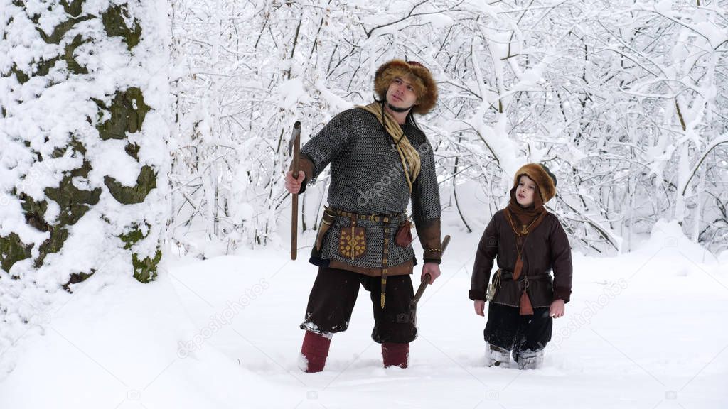 Father viking with his son in the winter forest