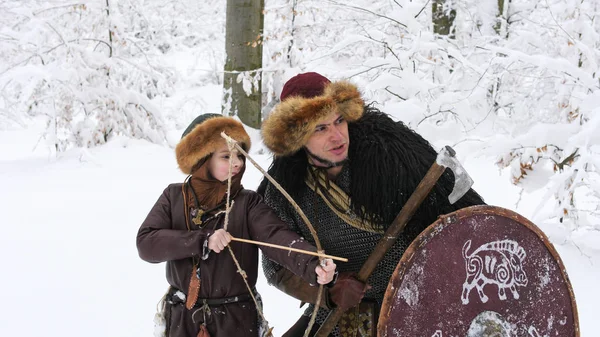 Otec Vikingové učí svého syna lukostřelbě v zimním lese. — Stock fotografie
