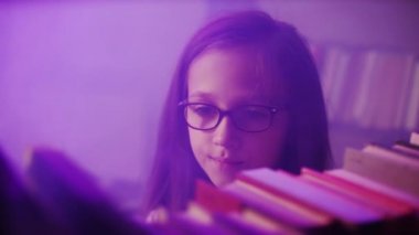 Yakın plan. Bir kız kütüphanenin raflarındaki kitapları düzenliyor..