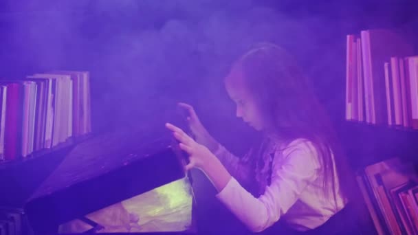 Meisje opent een magische kist waaruit licht en gekleurde rook barsten — Stockvideo