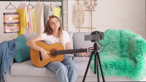 Atractiva chica adolescente Vlogging durante el juego en una guitarra.Young Girl Conduct Remote Teaching to Play on a Guitar During Blogging. Joven bastante Vlogger Hablando de Música. — Vídeo de stock