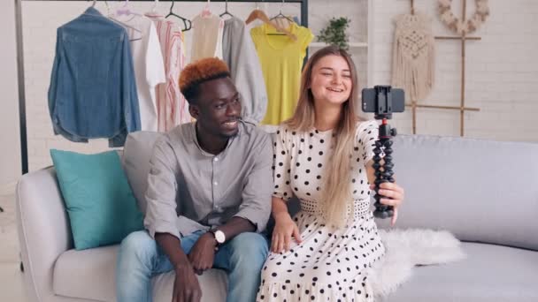 Cute Lady and Young Man comparte las noticias con sus seguidores durante el vlogging. Una chica y un niño toman fotos de sí mismos y hablan bien mientras están sentados en el sofá. — Vídeos de Stock