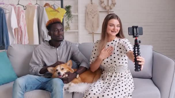 Ein Mädchen und ein Junge machen Fotos von sich, bloggen. Ein Mann streichelt einen süßen Hund, während er Videoblog dreht. Videoübertragung für Abonnenten zu Hause über Haustiere. — Stockvideo