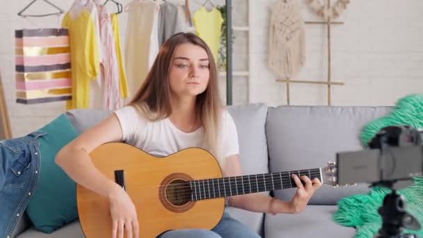 Atractiva chica adolescente Vlogging durante el juego en una guitarra.Young Girl Conduct Remote Teaching to Play on a Guitar During Blogging. — Vídeo de stock