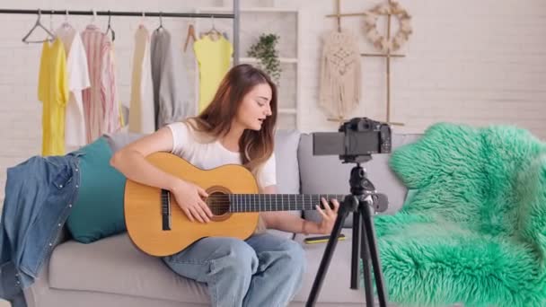 Una atractiva adolescente blogueando un video mientras toca la guitarra. — Vídeo de stock