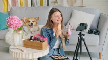 Makyaj yaparken sevimli köpeğiyle gezen çekici genç kız. Güzellik videosunu çeken genç kız. Genç Kız Blog Yazarken Uzaktan Kumanda Öğreticiliği Yapıyor.