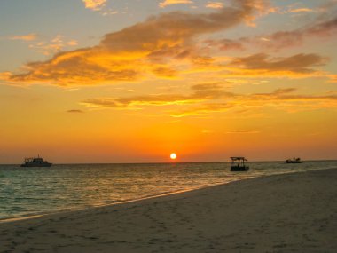 Maldivler arka plan. Günbatımı ile renkli bulutlar gökyüzünde mercan beach ve tropikal deniz üzerinde. Tekneler, barış ve gevşeme göksel atoll içinde ufukta. Kuzey Erkek Atoll Asdu, Hint Okyanusu.