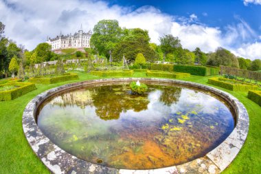 Yuvarlak flowerbed havuzu bahçe Dunvegan Kalesi'nde Dunvegan City, mavi gökyüzü güneşli bir günde Isle of Skye, İskoçya, Birleşik Krallık. Dunvegan Loch içinde İskoçya'nın dağlık. Geniş açı.
