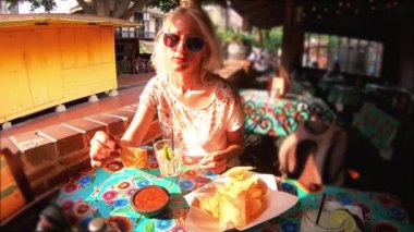 Ağır çekim: Neşeli sarışın kadın tipik Meksika yemeği, içinde geleneksel restoran El Pueblo, Los Angeles şehir merkezinde State Historic Park, California, Amerika Birleşik Devletleri, chili soslu cips cips koyar.