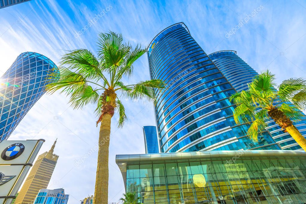 Doha, Qatar - February 17, 2019: perspective view of BMW sign at Alfardan Towers in West Bay commercial district. Skyscrapers in Doha Downtown, Middle East. Urban scene with palm trees.