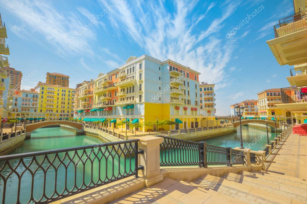Little Venice with canals connected by bridges in venetian style. Colorful houses in picturesque Qanat Quartier icon of Doha, Qatar at daylight. Venice at the Pearl, Persian Gulf, Middle East.