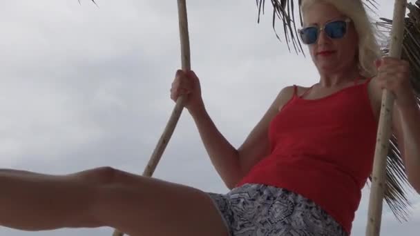 Ноги качаются на деревянных качелях на пляже — стоковое видео