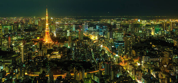 Panorama of Tokyo Skyline at night with illuminated iconic Tokyo Tower from Mori Tower, the modern skyscraper and tallest building of Roppongi Hills complex, Minato District, Tokyo, Japan. Aerial view