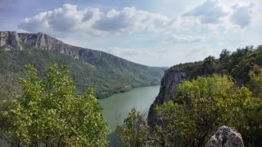 Tuna Nehri, Karpat dağları boyunca derin bir vadi oluşturarak, mavi gökyüzünün altındaki sarp yamaçları kaplayan yemyeşil ormanlarla Sırbistan ile Romanya arasında doğal bir sınır oluşturuyor.