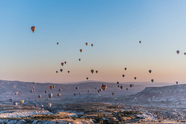View of hundred of hot air balloons flying all over Cappadocia region from the highest point in Uchisar during the sunrise in the morning, Turkey