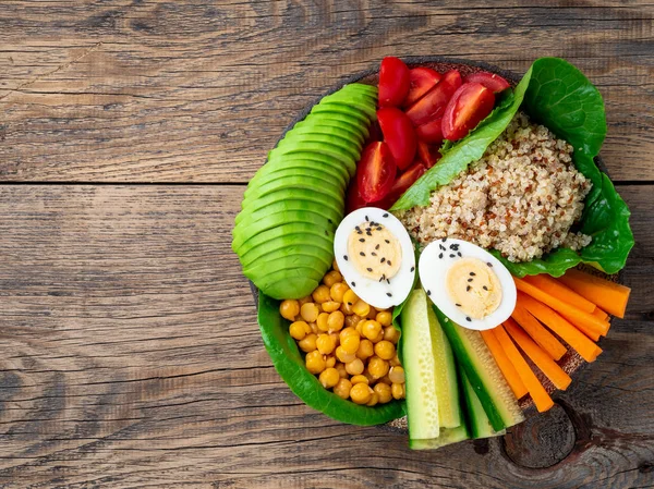Vegetarian Buddha\'s bowl, a mix of vegetables. Avocado, quinoa, chickpeas, vegetables, eggs, top view, copy space.