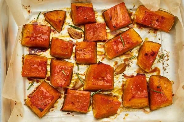 tray with roasted pieces of sweet pumpkin with honey and seasonings, top view
