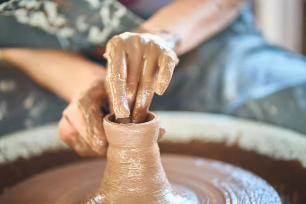 Woman making ceramic pottery on wheel, hands close-up, creation