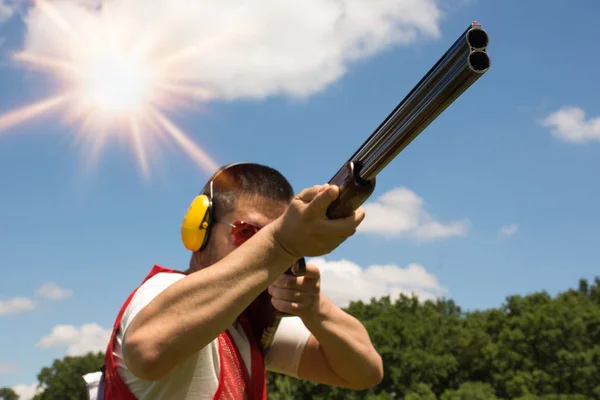 Homem atirando skeet com uma espingarda — Fotografia de Stock