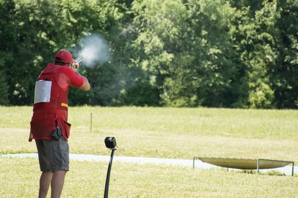 Homme tirant skeet avec un fusil Image En Vente