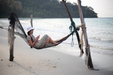 Kumsalda hamakta uyuyan bir kadın.