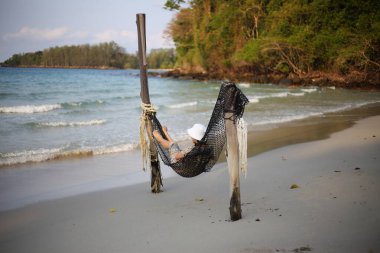 Kumsalda hamakta uyuyan bir kadın.