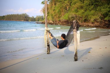 Sahilde hamakta uyuyan bir adam.