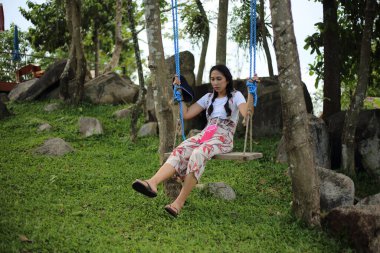 Bir kadın bahçede salıncakta oturuyor.